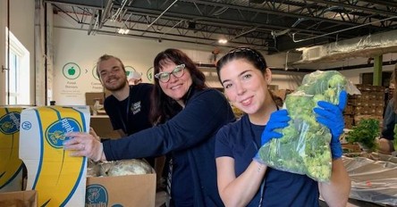 Staff and volunteers at NH Food Bank smiling at the camera while packing fresh food.